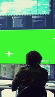 Vertical Team of IT military specialists working with a greenscreen on a big display, searching for real time data via reconnaissance CCTV system. Soldiers in power base transmitting information. Camera B. video