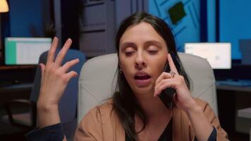 Exhausted entrepreneur discussing management graphs gesturing during negotiations phone call working late at night in company office. Entrepreneur man planning business interview video