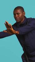 Vertical Security guard doing stop sign gesturing, being tasked with preventing public access in restricted area. Portrait of stern bodyguard pushing back unwanted visitors, studio background, camera B video