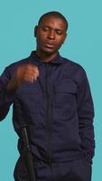 Vertical Security guard doing stop sign gesturing, being tasked with preventing criminal activity and detaining suspects. Portrait of stern bodyguard showing halt hand gesture, studio background, camera B video