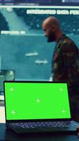 Vertical Commander examines a greenscreen on laptop in military command center, reconnaissance army division. Operator gathering intelligence from the field, transmitting real time data. Camera B. video