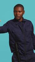 Vertical Portrait of security guard doing stop sign gesturing to intruder while overseeing premises. Private law enforcement worker showing halt hand gesture to trespasser, studio backdrop, camera B video