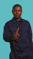 Vertical Security guard doing no gesturing with finger, prohibiting public access in restricted area. Portrait of stern bodyguard barring people from entering place, studio background, camera B video