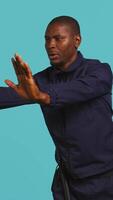 Vertical Portrait of security guard pushing back intruders while overseeing premises. Private law enforcement worker shoving away trespassers with hands, studio backdrop, camera B video