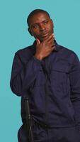 Vertical Security guard doing thinking hand gesture, being tasked with preventing criminal activity and detaining suspects. Portrait of pensive bodyguard rubbing chin, studio background, camera B video