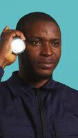 Vertical Headshot portrait of security guardian catching intruders with flashlight. Close up shot of private law enforcement employee detecting trespassers with lantern, studio backdrop, camera B video