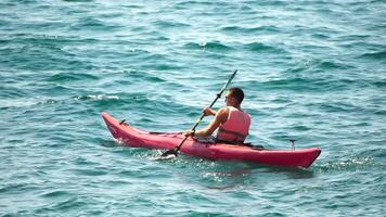 Man kayak Sea. Strong athletic man learns to paddle kayak in open sea ocean on sunny day. Summer holiday vacation and travel concept. Aerial view. Slow motion video