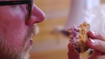 Man eating cheesecake. Bearded man in sunglases eating cheesecake on the beach. Happy man is smiling and resting at sea. Bearded guy enjoying meals on summer vacation. Slow motion. video