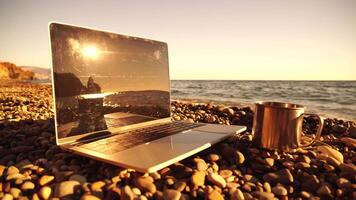 Silhouette of laptop and cup on the beach over sea sunset. Sparkling sea water on background. Freelancer, blogger working on notebook on the beach. video
