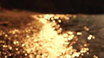 Abstract sea summer ocean sunset nature bokeh background. Small waves on azure water surface in motion blur with golden bokeh lights from sun. Holiday, vacation and recreational concept. Slow motion video