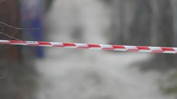 Red and white warning tape swinging in the wind. Protection sign. Don't cross the line. Red White caution tape pole fencing is protects for No entry. Backdrop without people, empty street. video