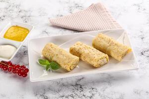 Homemade stuffed pancakes with honey and cream sour photo