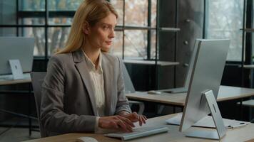 Female Caucasian adult freelancer lady employee businesswoman middle-aged woman secretary using modern wireless tech usage app. Office worker at desk texting on computer internet work online working photo