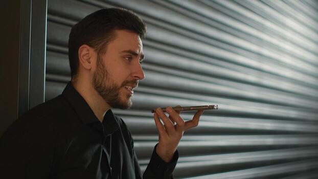 Caucasian man hold mobile phone talk calling say in speakerphone talking with loudspeaker record voice message give sound command AI tech smartphone male businessman guy recording voicemail in parking photo