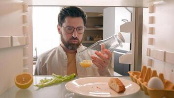Man open empty refrigerator with half lemon lettuce leaf one egg slice of bread leftover orange juice in bottle find solution order food delivery with mobile phone app point of view from inside fridge photo