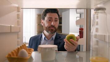 Point of view POV inside empty refrigerator Caucasian sad hungry businessman upset man open fridge with one egg empty bottle of juice searching snack take apple fruit diet need products food delivery photo