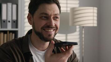 Smiling happy Caucasian man recording voice audio message send voicemail talk mobile phone loudspeaker business call in office businessman make heart love shape support symbol thanking love feelings photo
