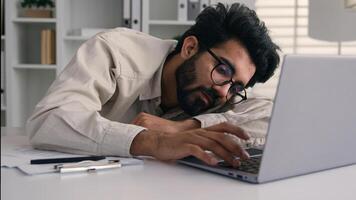 Lazy weary sleepy male manager tired exhausted Arabian Indian businessman employee working computer boring remote job man fall sleep on desktop napping in office overwork fatigue no energy sleeping photo