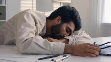 Lazy weary sleepy male manager tired exhausted Arabian Indian businessman employee working computer boring remote job man fall sleep on desktop napping in office overwork fatigue no energy sleeping photo