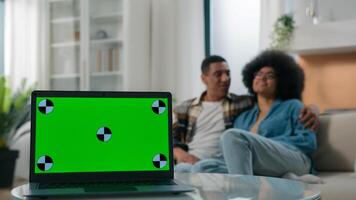 African American couple man woman hug relax at home couch girlfriend boyfriend cuddling hugging on sofa together smile blurred background laptop computer pc with empty mock up green screen copy space photo