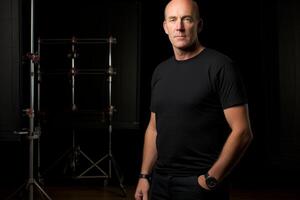 Portrait mature serious confident Caucasian bald man male fashion model black clothes background posing looking camera photo studio indoor professional photographer taking picture