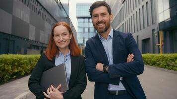Caucasian successful confident happy businesspeople business woman man looking at each other smiling look at camera posing hands crossed in city outdoors office building colleagues coworkers partners photo