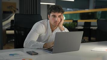 Tired exhausted Caucasian businessman bored fatigued male designer with computer project sad overworked overtime working at creative modern office business man employer work laptop boring deadline photo