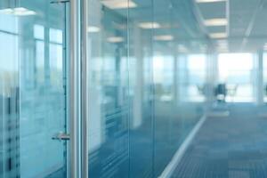 A large, empty office room with a sun shining through the windows. Modern space is made of glass and has a shiny, reflective surface photo
