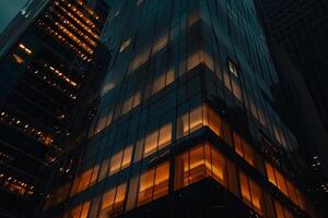 Modern office building windows lit in evening night early morning long working hours exhaustion overtime exterior urban architecture skyscraper lights tower financial sector banking hq photo