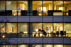 Modern office building windows lit in evening night early morning long working hours exhaustion overtime exterior urban architecture skyscraper lights tower financial sector banking hq photo