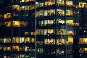 Modern office building windows lit in evening night early morning long working hours exhaustion overtime exterior urban architecture skyscraper lights tower financial sector banking hq photo