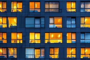 Modern office building windows lit in evening night early morning long working hours exhaustion overtime exterior urban architecture skyscraper lights tower financial sector banking hq photo