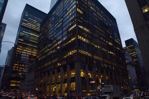 Modern office building windows lit in evening night early morning long working hours exhaustion overtime exterior urban architecture skyscraper lights tower financial sector banking hq photo