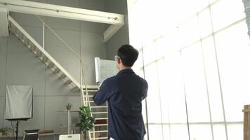 A man is standing in a room with a white wall and a white door. He is holding a piece of paper and he is reading it. The room has a modern design with a white color scheme video