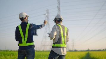 Two men are standing in a field, one of them is talking on a cell phone. The other man is holding a clipboard and looking up at the sky. Scene is serious and focused video