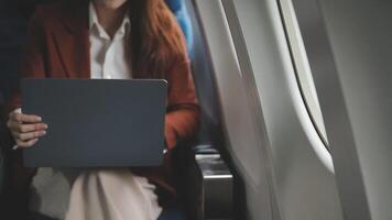 Traveling and technology. Flying at first class. Pretty young businees woman working on laptop computer while sitting in airplane. video