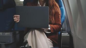 Traveling and technology. Flying at first class. Pretty young businees woman working on laptop computer while sitting in airplane. video