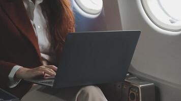Traveling and technology. Flying at first class. Pretty young businees woman working on laptop computer while sitting in airplane. video