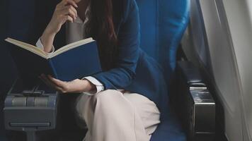 Asian business woman passenger sitting on business class luxury plane while working using smart phone mobile talking and use notebook while travel concept. video
