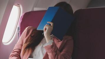 Asian business woman passenger sitting on business class luxury plane while working using smart phone mobile talking and use notebook while travel concept. video