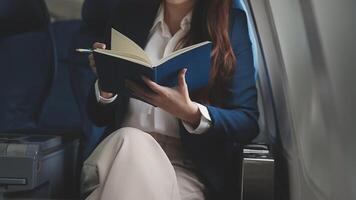 Asian business woman passenger sitting on business class luxury plane while working using smart phone mobile talking and use notebook while travel concept. video