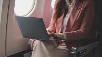 Traveling and technology. Flying at first class. Pretty young businees woman working on laptop computer while sitting in airplane. video