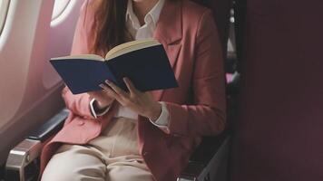 Asian business woman passenger sitting on business class luxury plane while working using smart phone mobile talking and use notebook while travel concept. video