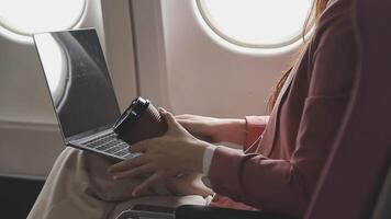 Traveling and technology. Flying at first class. Pretty young businees woman working on laptop computer while sitting in airplane. video