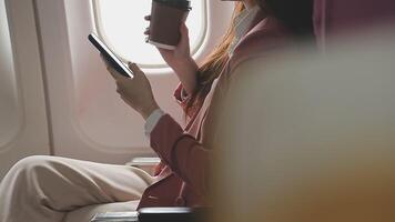 Asian business woman passenger sitting on business class luxury plane while working using smart phone mobile talking and use notebook while travel concept. video