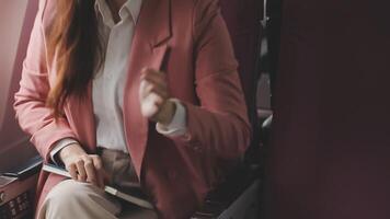 Asian business woman passenger sitting on business class luxury plane while working using smart phone mobile talking and use notebook while travel concept. video