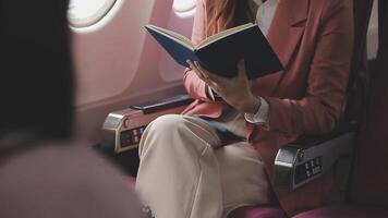 Asian business woman passenger sitting on business class luxury plane while working using smart phone mobile talking and use notebook while travel concept. video
