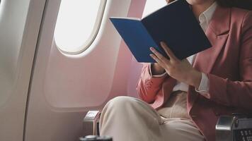 Asian business woman passenger sitting on business class luxury plane while working using smart phone mobile talking and use notebook while travel concept. video