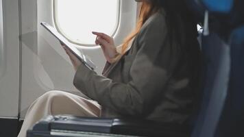 Asian business woman passenger sitting on business class luxury plane while working using smart phone mobile talking and use notebook while travel concept. video
