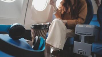 An Asian businesswoman in a semi-formal suit is using a tablet to read and analyze business data while traveling to a meeting in business class on a plane. video